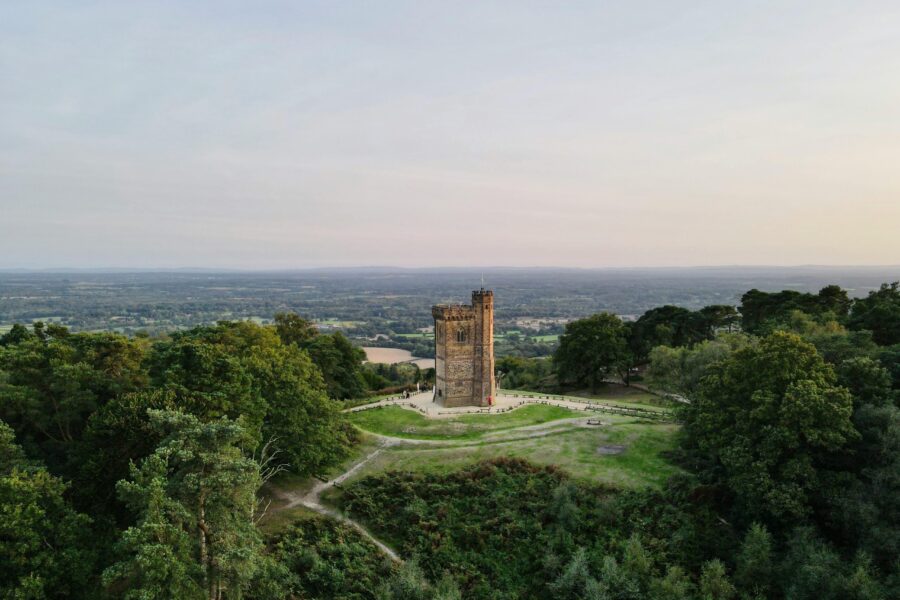 This picutre shows a gothic medieval tower on green hill under a sundown sky.