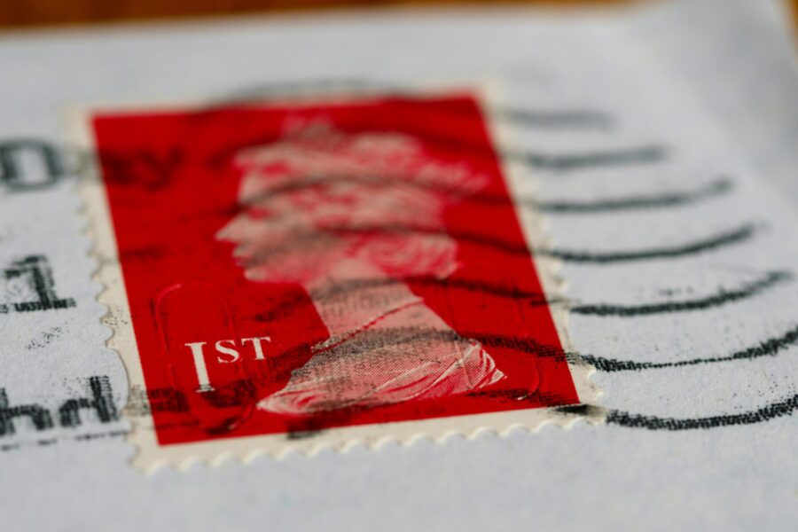 This picture shows a close up of a royal mail stand, it is red and first class.